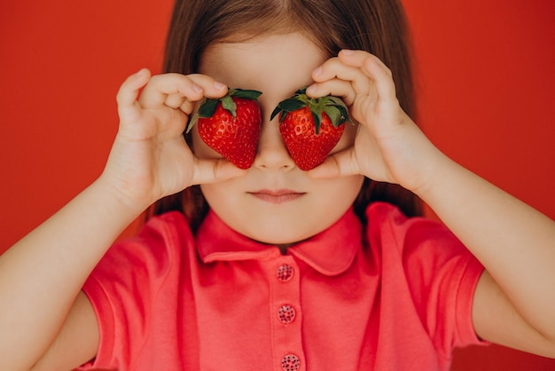 Niña sosteniendo dos fresas deliciosas