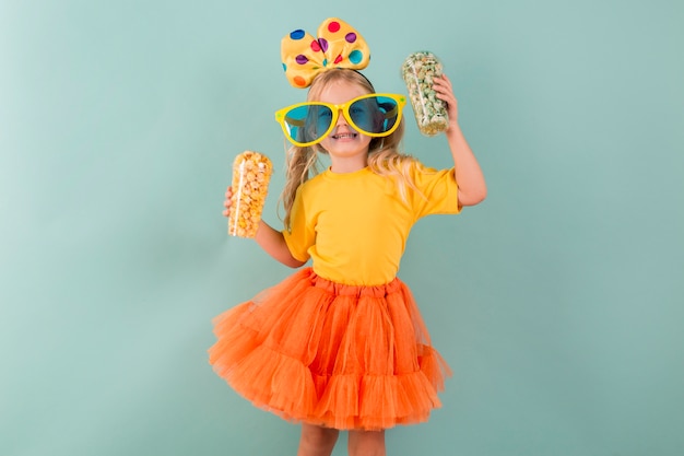 Niña sosteniendo dulces mientras usa grandes gafas de sol