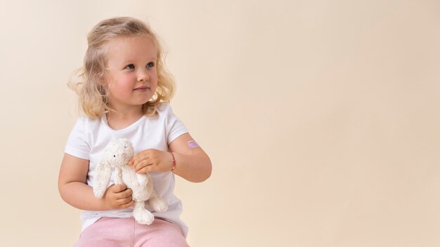 Niña sosteniendo un juguete después de recibir una vacuna