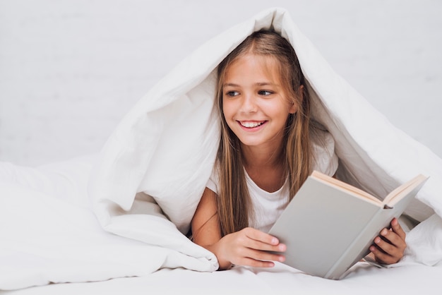 Niña sosteniendo un libro mientras mira lejos