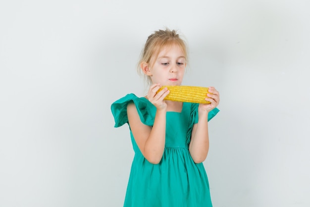 Foto gratuita niña sosteniendo maíz en vista frontal vestido verde.