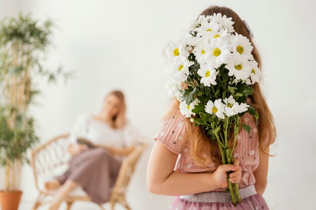 Niña sosteniendo un ramo de flores de primavera como sorpresa para su madre