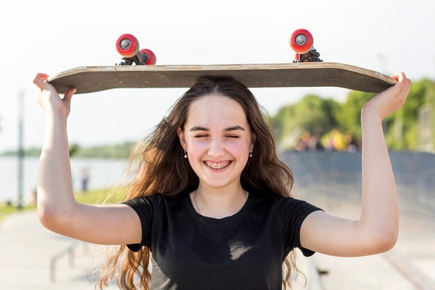 Niña sosteniendo su patineta sobre su cabeza