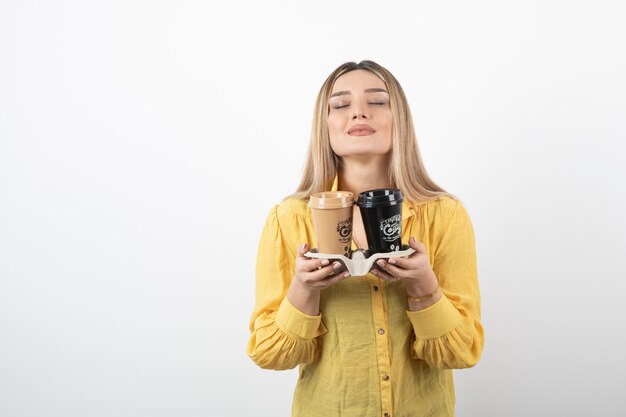 niña sosteniendo tazas de café y las huele.