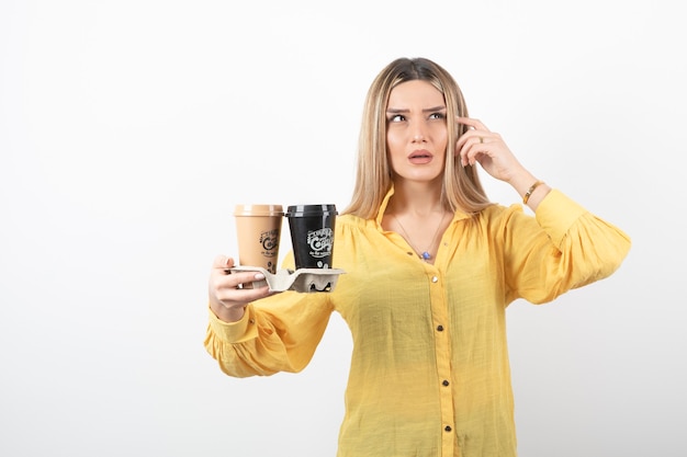 niña sosteniendo tazas de café y pensando.