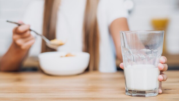 Niña sosteniendo un vaso de leche mientras come cereal