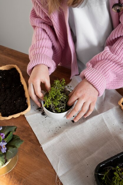 Niña sosteniendo vegetación plantada en maceta reciclada