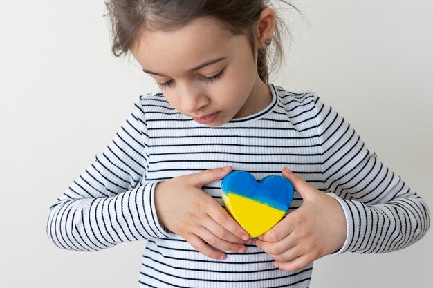 Una niña sostiene un corazón pintado con los colores de la bandera de ucrania