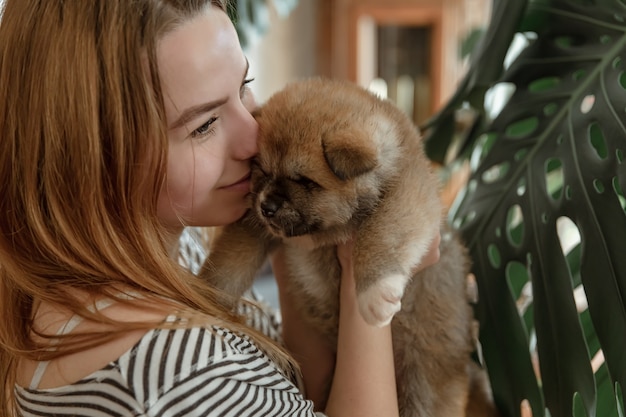 La niña sostiene un pequeño cachorro recién nacido esponjoso en sus brazos