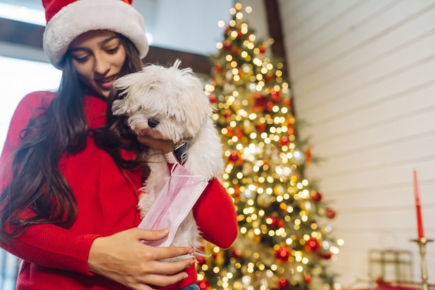 Una niña sostiene un pequeño perro en sus manos en la víspera de Año Nuevo con un amigo