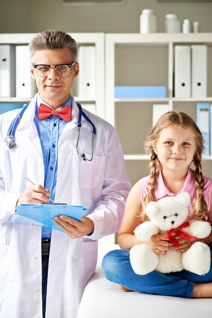 Niña con su osito de peluche en la consulta del médico