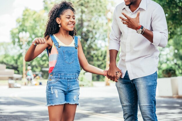 Niña con su padre pasar un buen rato juntos en un paseo al aire libre en la calle