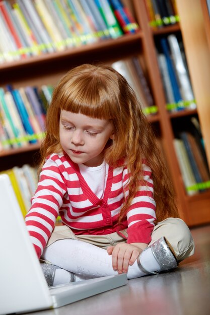 Niña en el suelo con un ordenador portátil