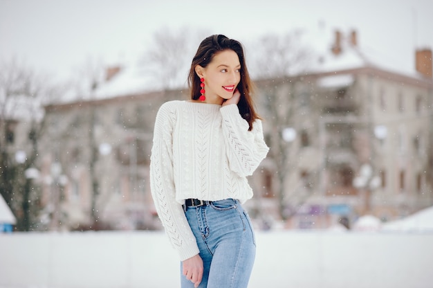 Niña en un suéter blanco de pie en un parque de invierno