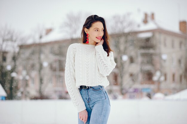 Niña en un suéter blanco de pie en un parque de invierno