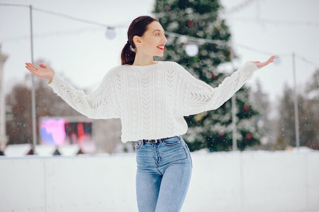 Niña en un suéter blanco de pie en un parque de invierno