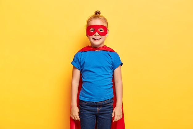 La niña superheroína viste un traje especial con capa roja