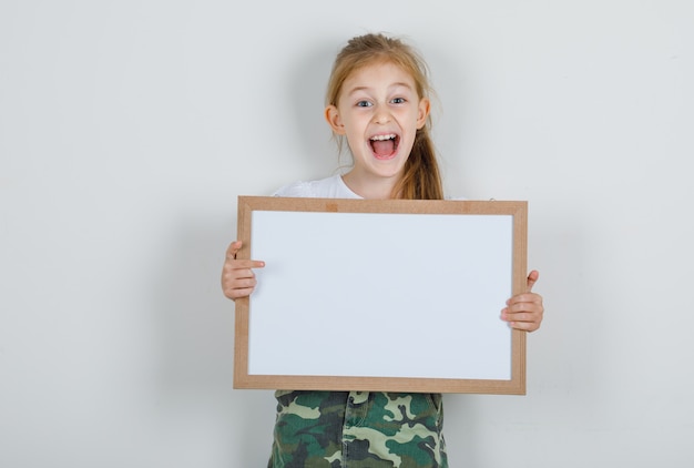 Niña con tablero blanco en camiseta blanca