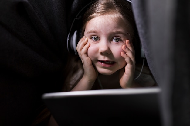 Foto gratuita niña con tablet debajo de manta