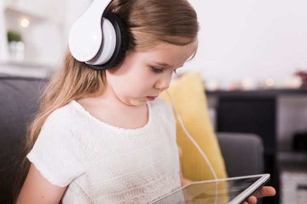 Niña con tablet en sofá