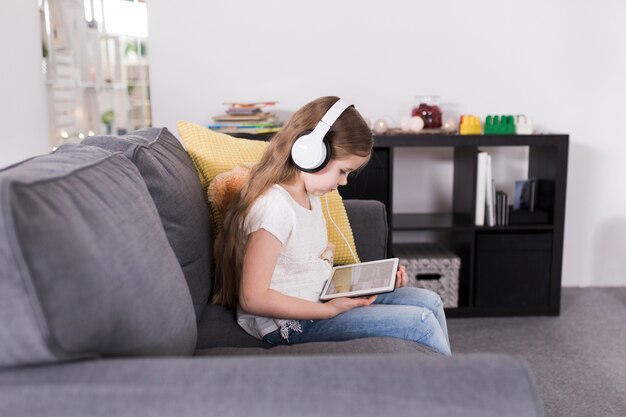 Niña con tablet en sofá