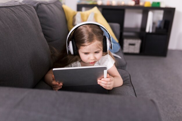 Niña con tablet tumbada en sofá