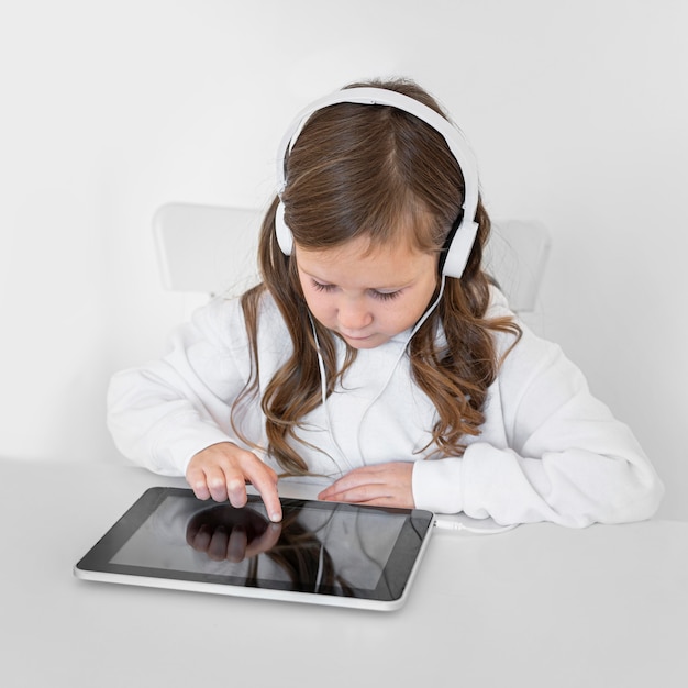 Foto gratuita niña con tableta con auriculares