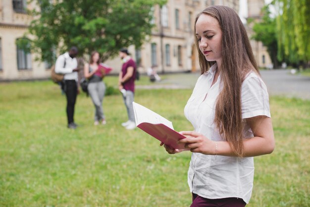 Niña, tenencia, cuaderno, lectura, posición, exterior