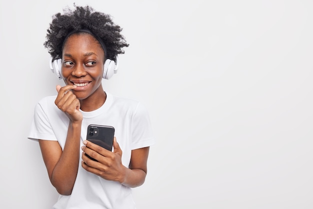 la niña tiene una aplicación de música escucha una gran canción en línea usa una camiseta informal se comunica en línea va a tener poses de lecciones web remotas en blanco