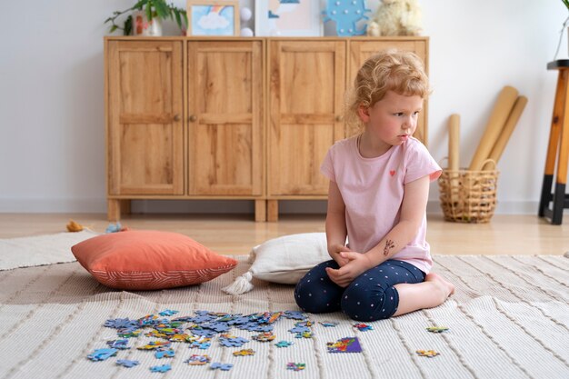 Niña de tiro completo haciendo rompecabezas en el piso