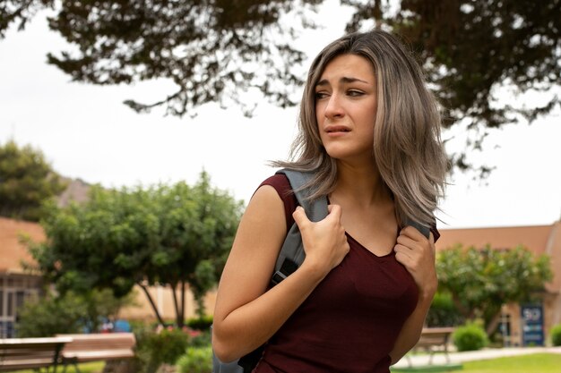 Niña de tiro medio llorando en el patio de la escuela