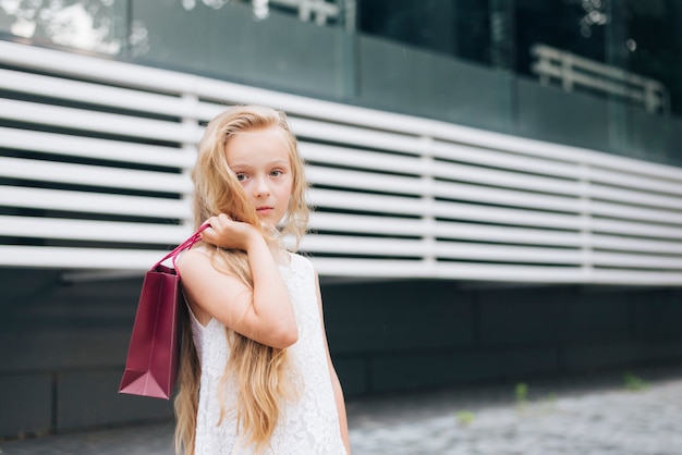 Niña de tiro medio posando con bolsa de regalo