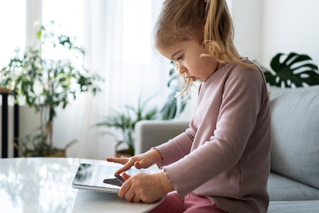 Foto gratuita niña de tiro medio con tableta en casa