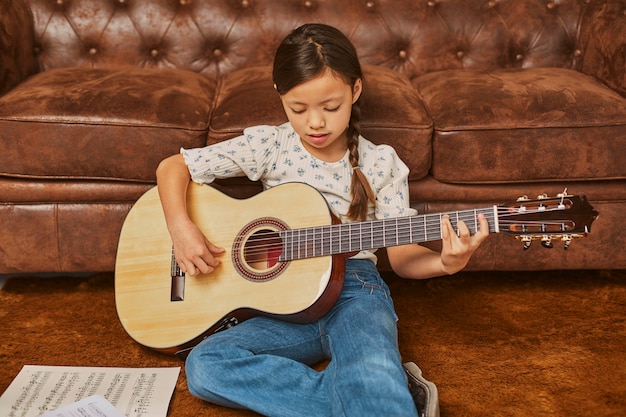 Niña tocando la guitarra en casa