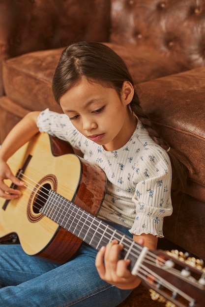 Foto gratuita niña tocando la guitarra en casa