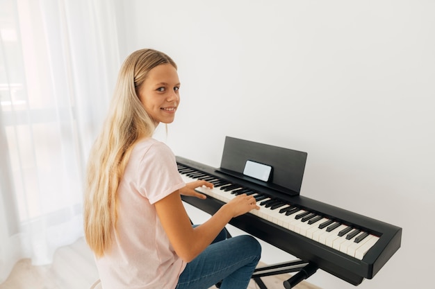 Foto gratuita niña tocando el instrumento de teclado en casa