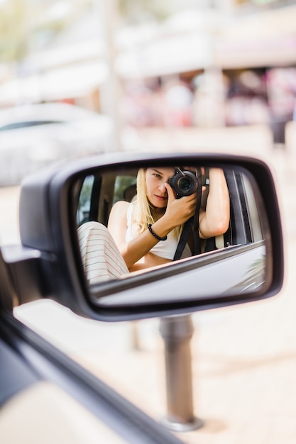 Una niña se toma una foto de sí misma en el espejo de un auto.