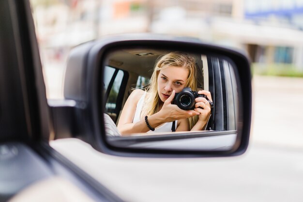 Una niña se toma una foto de sí misma en el espejo de un auto.