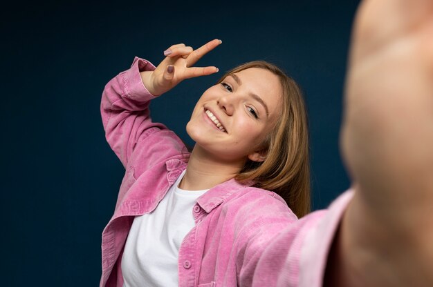 Niña tomando un selfie de sí misma mientras muestra el signo de la paz