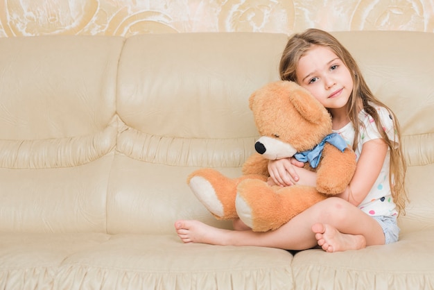 Foto gratuita niña tranquila abrazando oso de peluche