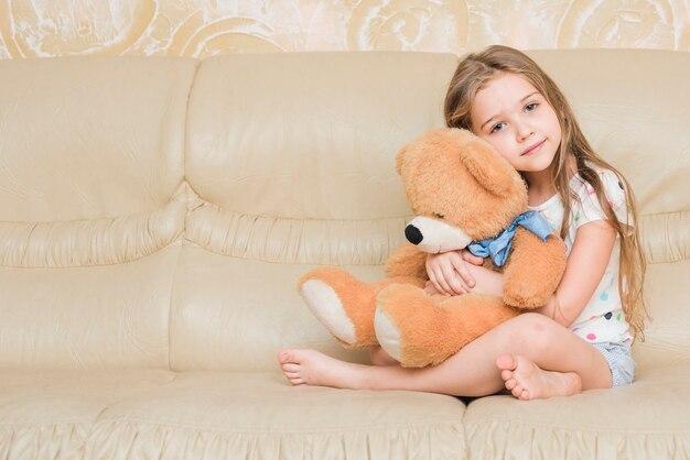 Niña tranquila abrazando oso de peluche