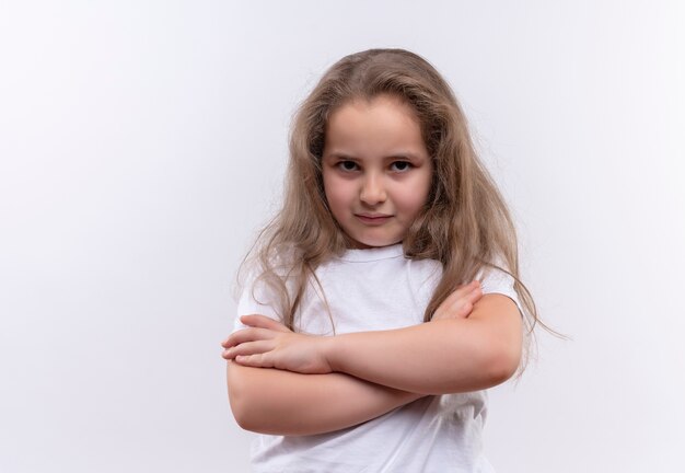 Niña triste de la escuela con camiseta blanca cruzando las manos sobre fondo blanco aislado