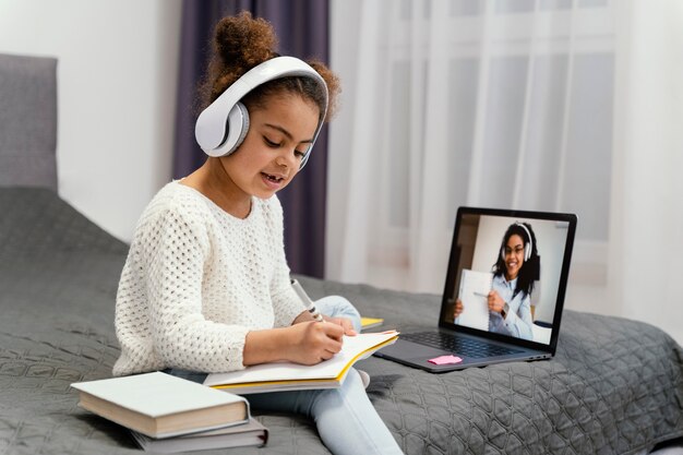 Niña usando laptop para escuela en línea