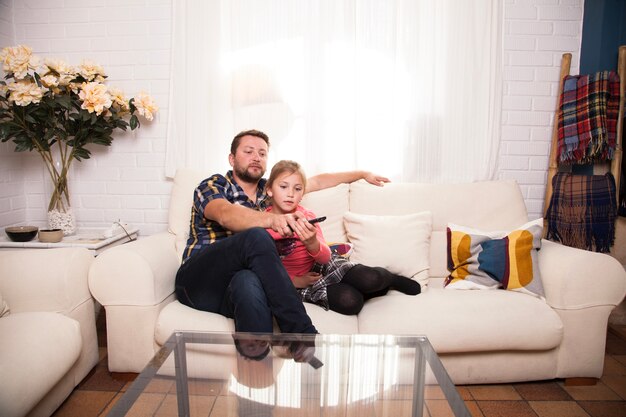 Niña usando el mando a distancia junto a su padre