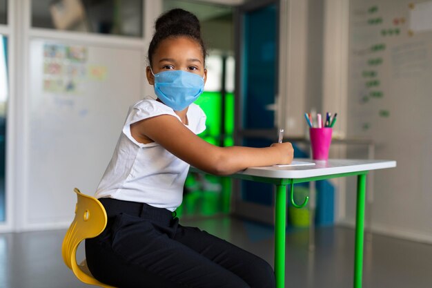 Niña usando una máscara médica en clase