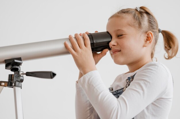 Niña usando un telescopio en clase