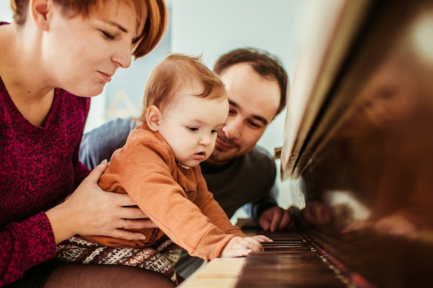 Foto gratuita niña se ve divertida jugando con la madre en el piano