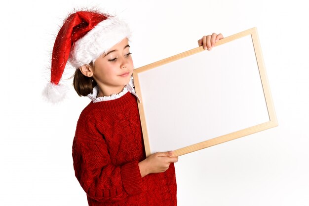 Niña vestida de papa noel sujetando una pizarra blanca