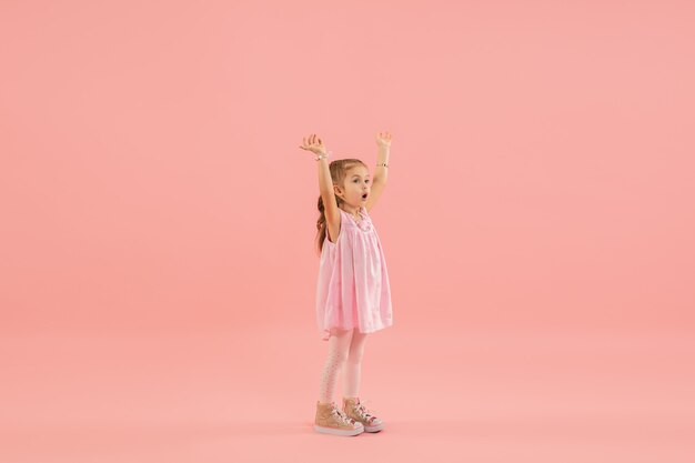 Niña en vestido rosa en pared rosa