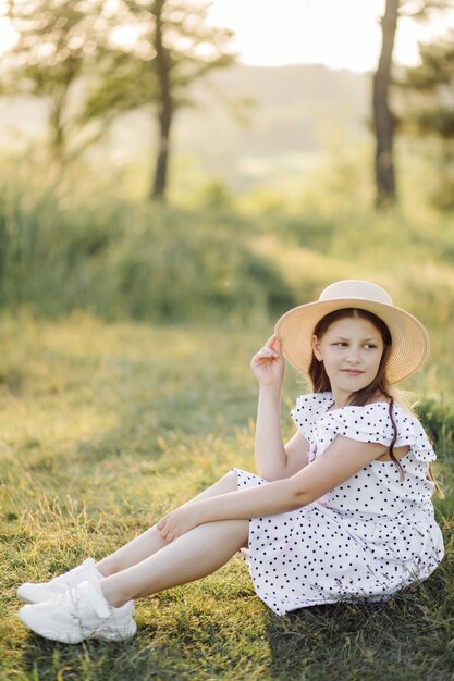 Una niña con un vestido y un sombrero se encuentra en el campo.